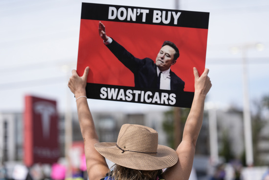 Jennifer Walker stands with other demonstrators during a protest of automaker billionaire CEO, Elon Musk near a Tesla vehicle dealership, Saturday, March 8, 2025, in Decatur, Ga. (AP Photo/Mike Stewart)