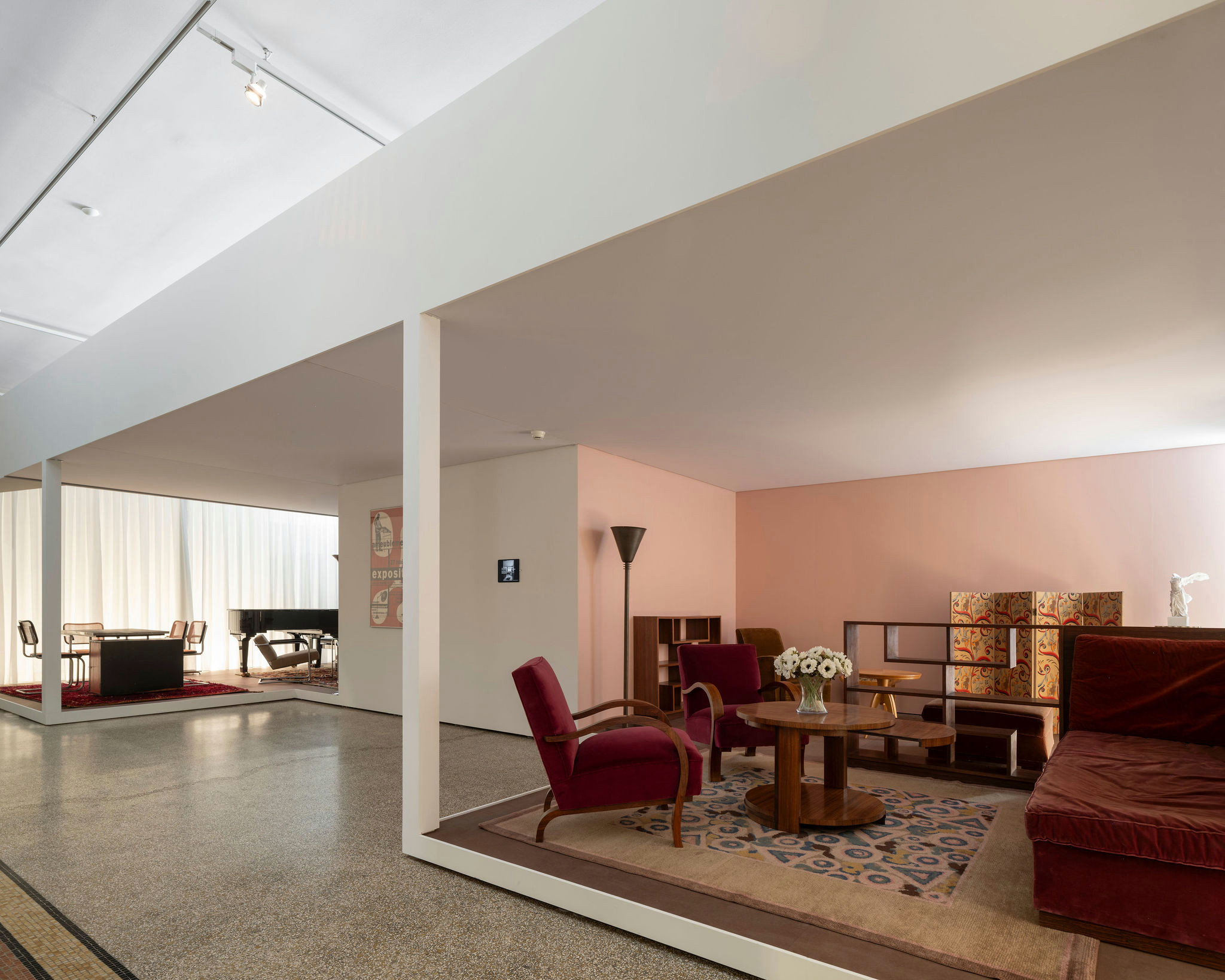 Salle d’exposition présentant des meubles modernes dans un espace épuré avec des murs blancs et un sol en terrazzo.