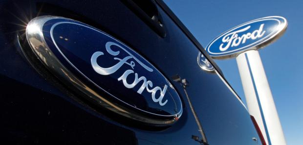 A Ford logo is on the tailgate of a pick-up truck and on a Ford dealership sign in Salem, N.H. (AP Photo/Charles Krupa, File)