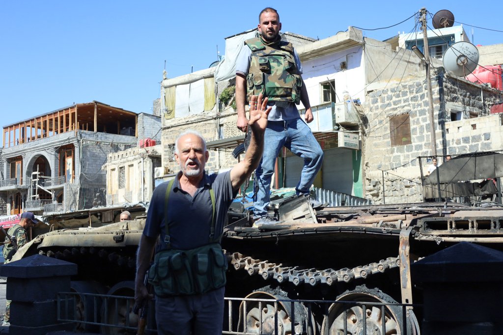 Syrian Druze fighters celebrate atop a damaged army military vehicle, after Syrian government forces pulled out of the southern Sweida governorate, on July 17, 2025. The Druze heartland Sweida has been gripped by deadly sectarian bloodshed since July 13, with hundreds reportedly killed in clashes pitting Druze fighters against Sunni Bedouin tribes and the army and its allies. (Photo by Shadi AL-DUBAISI / AFP) (Photo by SHADI AL-DUBAISI/AFP via Getty Images)