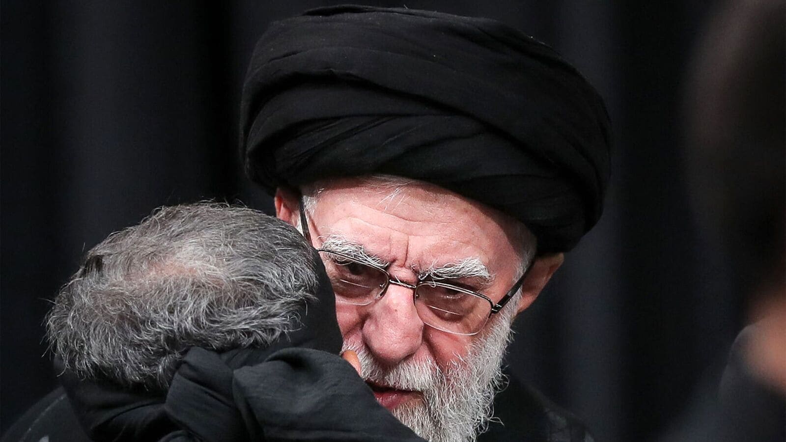 This handout picture released by the office of Iran's Supreme Leader Ayatollah Ali Khamenei on July 5, 2025 shows him embracing a mourner during a mourning ceremony in Tehran marking the ninth day of the Islamic month of Muharram in the lead-up to Ashura, a 10-day period commemorating the seventh century killing of Prophet Mohammed's grandson Imam Hussein. (Photo by LEADER OFFICE / AFP)