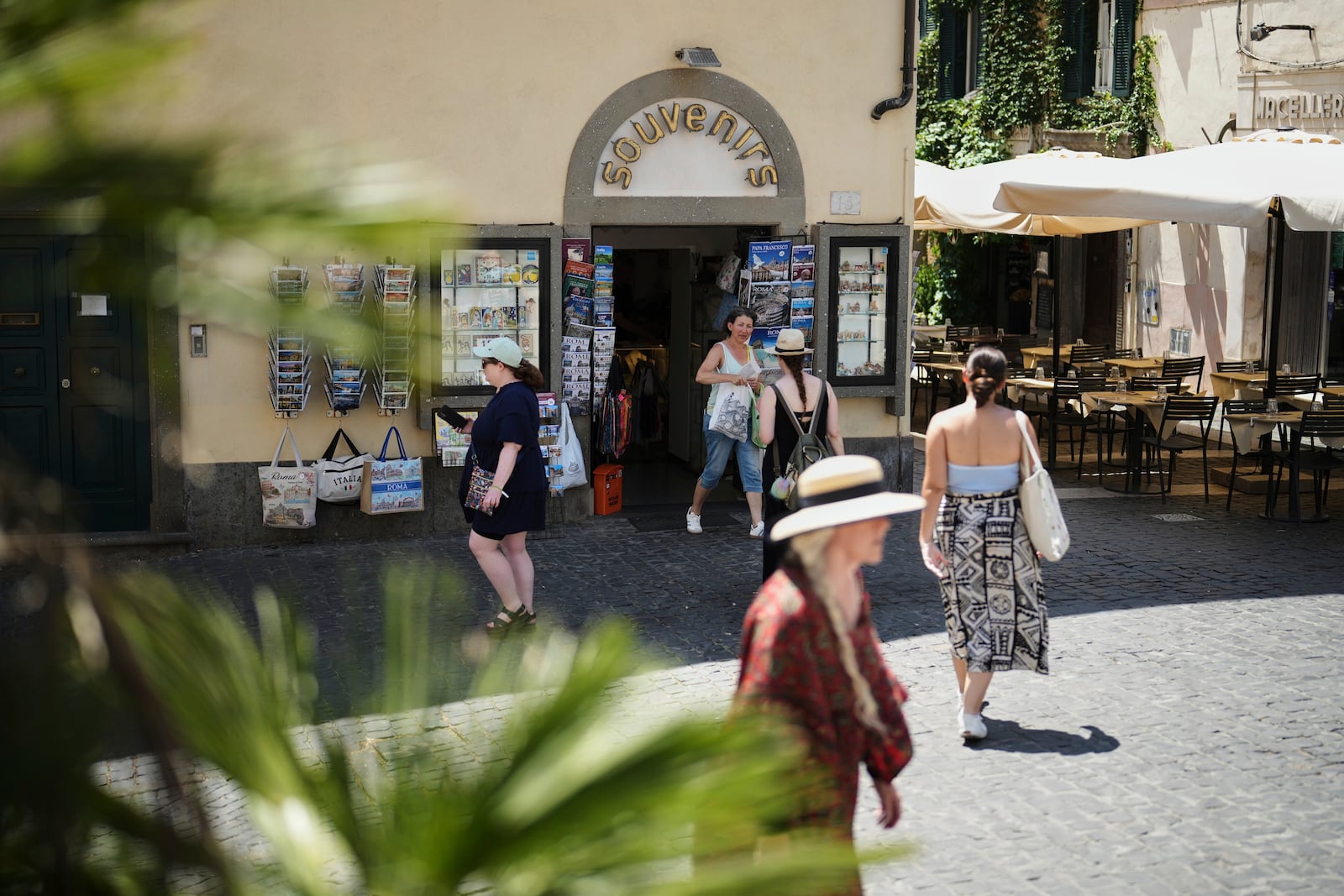 People walk past a souvenir shop in the town of Castel Gandolfo, a historic summer retreat for popes about 30 kilometers southeast of Rome, where Pope Leo XIV will be spending a short period of rest, is seen Wednesday, July 2, 2025. (AP Photo/Andrew Medichini)
