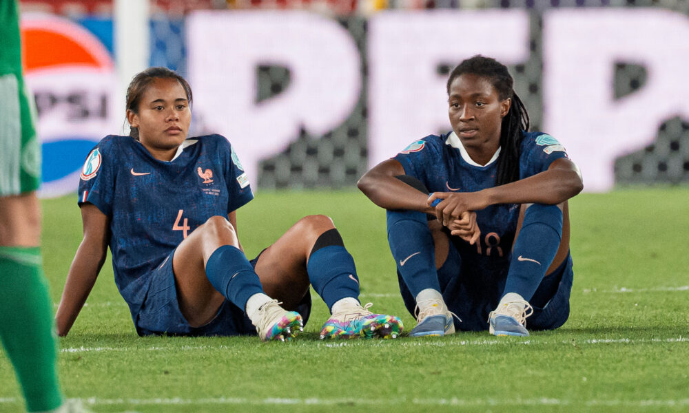 Oriane Jean-Francois and Alice Sombath sit on the pitch at St. Jakob-Park in Basel, Switzerland after losing to Germany on penalties in the UEFA Women's Euro 2025 quarterfinal.