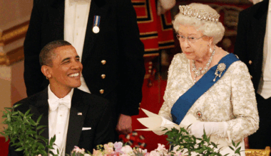 Queen Elizabeth wearing a tiara giving a speech standing up at a banquet table next to Barack Obama