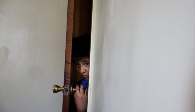 Ery Perez Gutierrez, 9, peered through the door into the living room of his family’s apartment in Springfield on July 15. Ery participated in a summer program last year but since President Trump froze education funds for the Migration Education Program, a grant that supports children of agricultural and fishery workers, he has had to stay home instead.