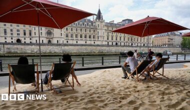 Parisians sit on deckchairs beside the Seine