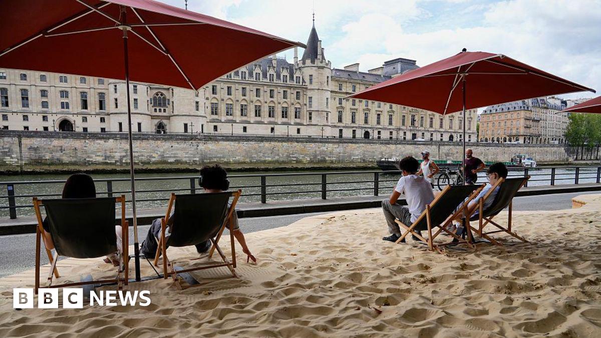Parisians sit on deckchairs beside the Seine