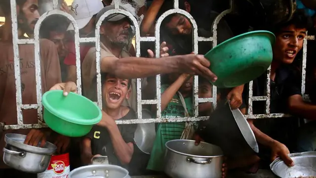 Varios palestinos se agolpan para recibir una comida caliente en un comedor social, al sur de la Franja de Gaza.