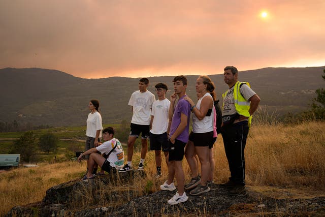 People watch the firefighting efforts as the fire progresses in A Caniza, Pontevedra province, north-west Spain