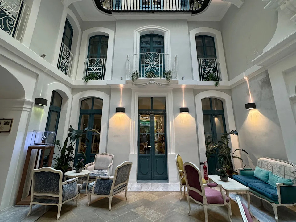 An elegant interior courtyard with balconies, small tables, and chairs.