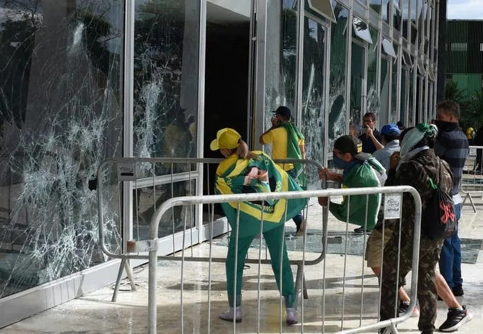People in sports attire break windows of a modern building with metal barriers