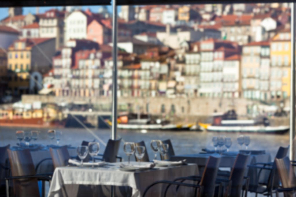 Blurry photo of restaurant tables set for service with a view of a city waterfront.