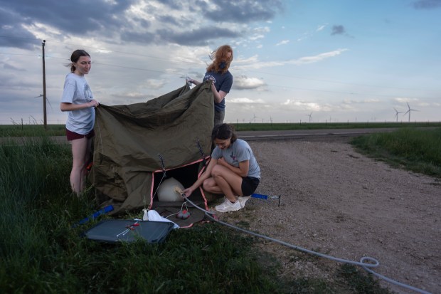 Project ICECHIP members from Northern Illinois University Evelynn Mantia, left, and Olivena Carlisle, lower right, inflate a weather balloon with a radiosonde attached to collect data, June 4, 2025, during a hail study in Tucumcari, New Mexico. (Carolyn Kaster/AP)