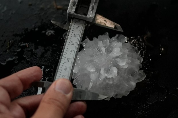 Forensic engineer Tim Marshall measure a large hail in the front seats of Northern Illinois University's Husky Hail Hunter during a Project ICECHIP operation, June 6, 2025, in Morton, Texas. Project ICECHIP is made of teams from several universities observing storms from the inside and seeing how the hail forms. (Carolyn Kaster/AP)