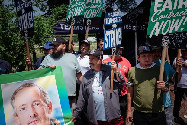 Teamsters Local 705 members at Mauser Packaging Solutions hold a banner with the image of Mauser CEO Mark Burgess as they strike over working conditions and immigration concerns at the facility in the Little Village neighborhood, July 21, 2025. (E. Jason Wambsgans/Chicago Tribune)