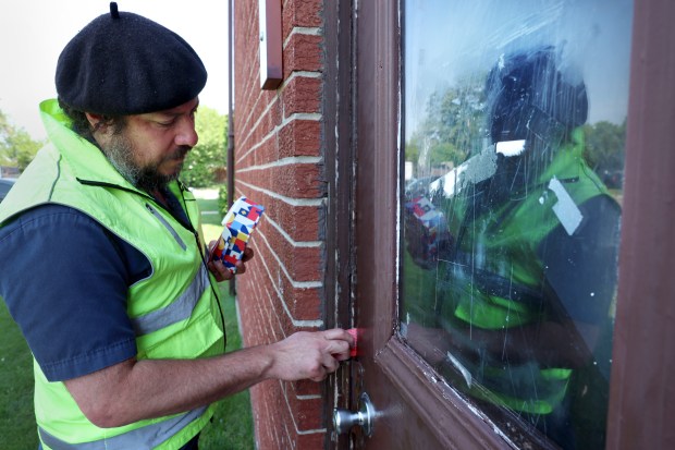 Cristobal Cavazos, co-founder of Immigrant Solidarity DuPage and Casa Dupage Workers Center, goes door-to-door handing out "know your rights" cards for families residing in the Elm Court Apartments on July 21, 2025, in Bensenville. (Stacey Wescott/Chicago Tribune)