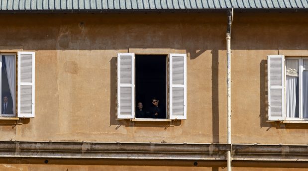 Priests watch from a window as Pope Leo XIV arrives for his installation Mass in St. Peter's Square on May 18, 2025, at the Vatican. (Brian Cassella/Chicago Tribune)