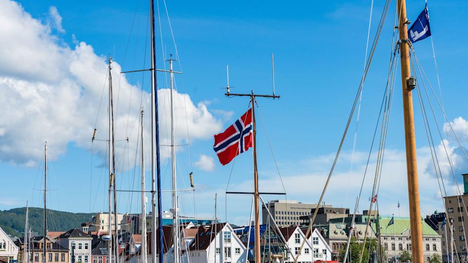 Bergen, Norway - July 9, 2024: Norwegian flag and yacht masts in harbor against clear blue sky