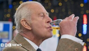 King Charles, with his lips pursed as he sips from a glass of whisky