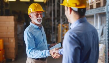 two men wearing yellow construction helmets shaking hands