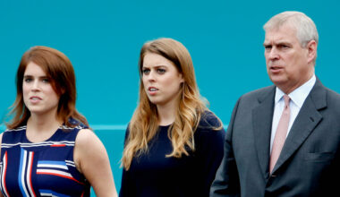 Princess Eugenie and Princess Beatrice wear striped dresses as they walk with their father Prince Andrew, who is wearing a dark suit with a pink tie