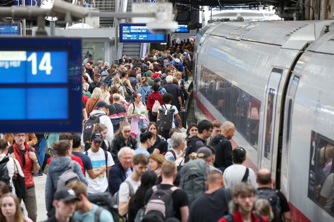 Zahlreiche Reisende sind auf vollen Bahnsteigen unterwegs.