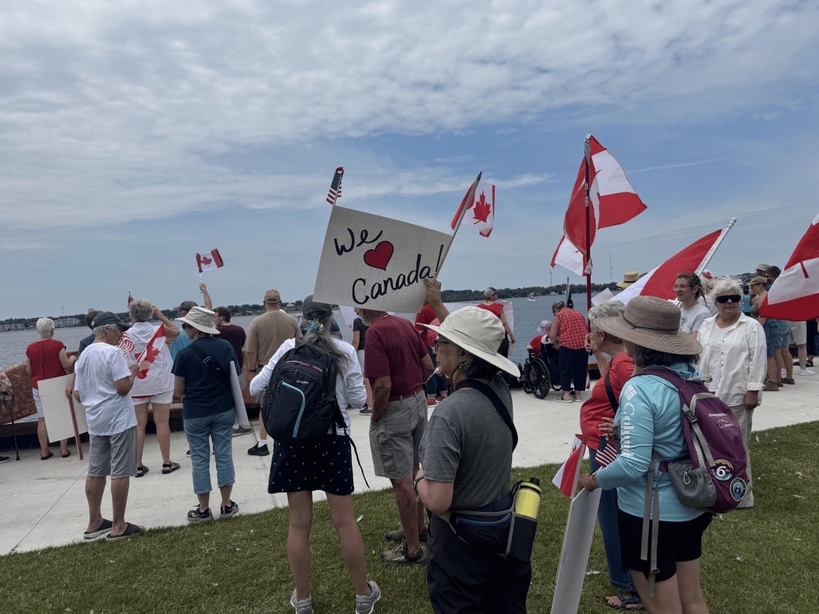 Woman holds a sign that says we love Canada, with the word "love" being replaced with a heart.