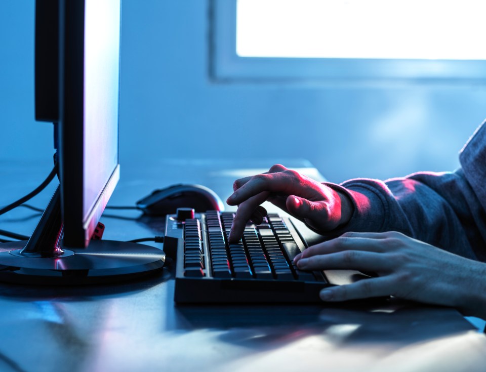 Close-up of a teenager's hands typing on a computer keyboard.