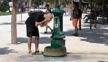 Ein Mann steht gebückt vor einem Trinkbrunnen und erfrischt sich mit dem kalten Wasser.
