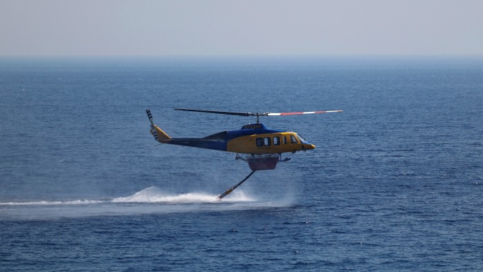 A firefighting helicopter picks up water from the sea, as a wildfire burns near Ierapetra, on the island of Crete, Greece on July 3 2025