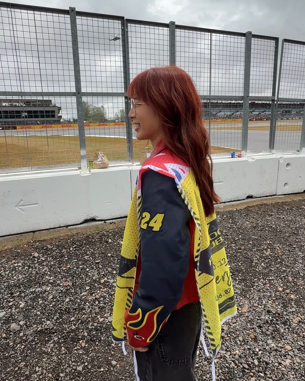 a woman stands in front of a racetrack.