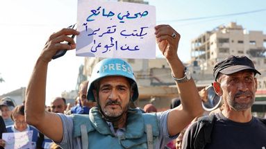 Un manifestant brandit une pancarte sur laquelle on peut lire en arabe "un journaliste affamé écrit un reportage sur les affamés", lors d'une manifestation de journalistes contre la faim dans le quartier de Rimal, à Gaza, le 19 juillet 2025.