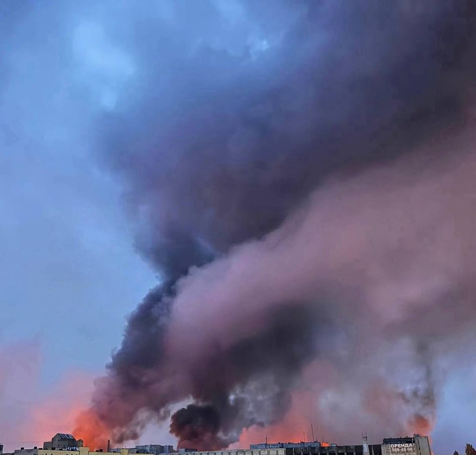Large plume of smoke rising from a fire in a city.