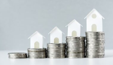 Small white wooden houses on top of increasingly large piles of silver coins