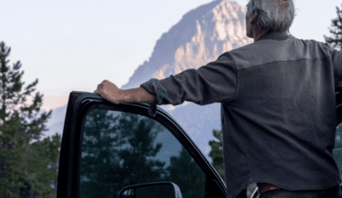A man with his car door open looking at a stunning mountain