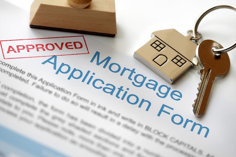 Approved mortgage loan application with house key and rubber stamp