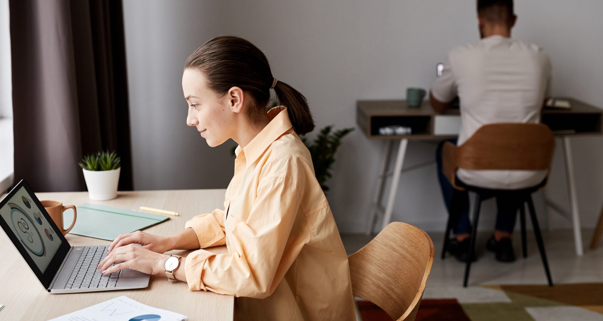 Side view of young confident brunette businesswoman looking at graphic data