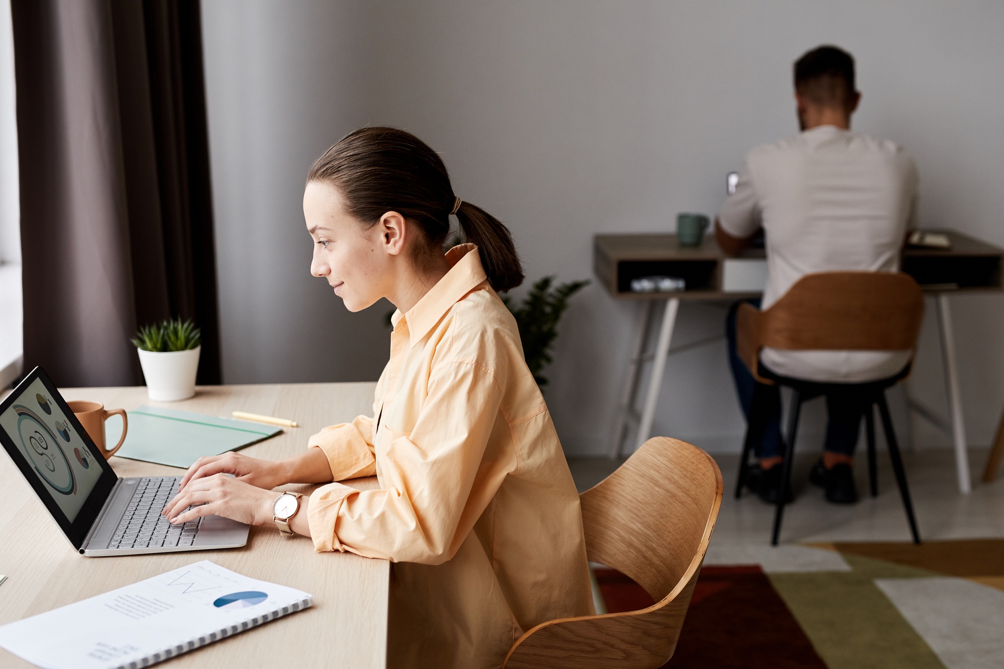 Side view of young confident brunette businesswoman looking at graphic data