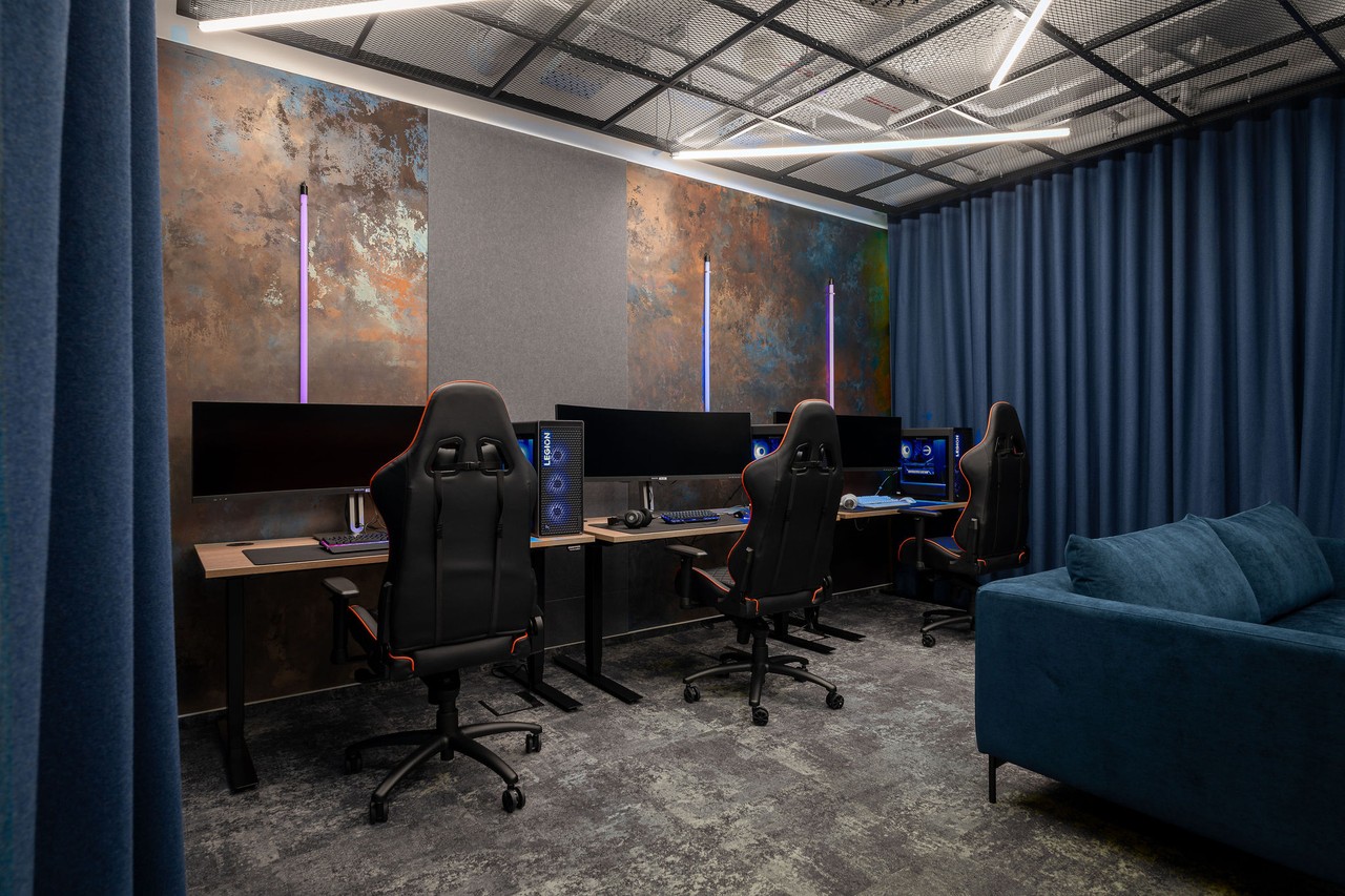 Nowoczesne biuro gamingowe z designerskimi fotelami i oświetleniem.