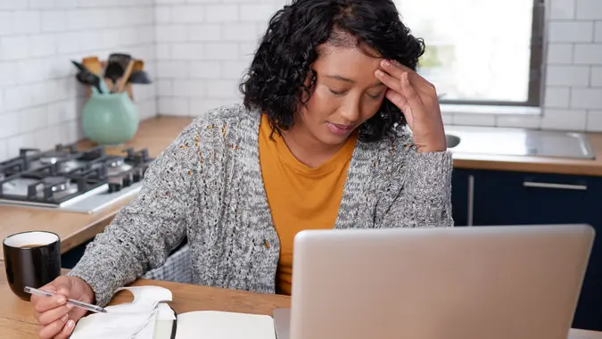 A young multi-ethnic woman is stressed while calculating household expenses
