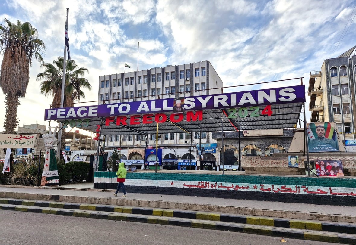A city square featuring a banner that says 'Peace to all Syrians.'