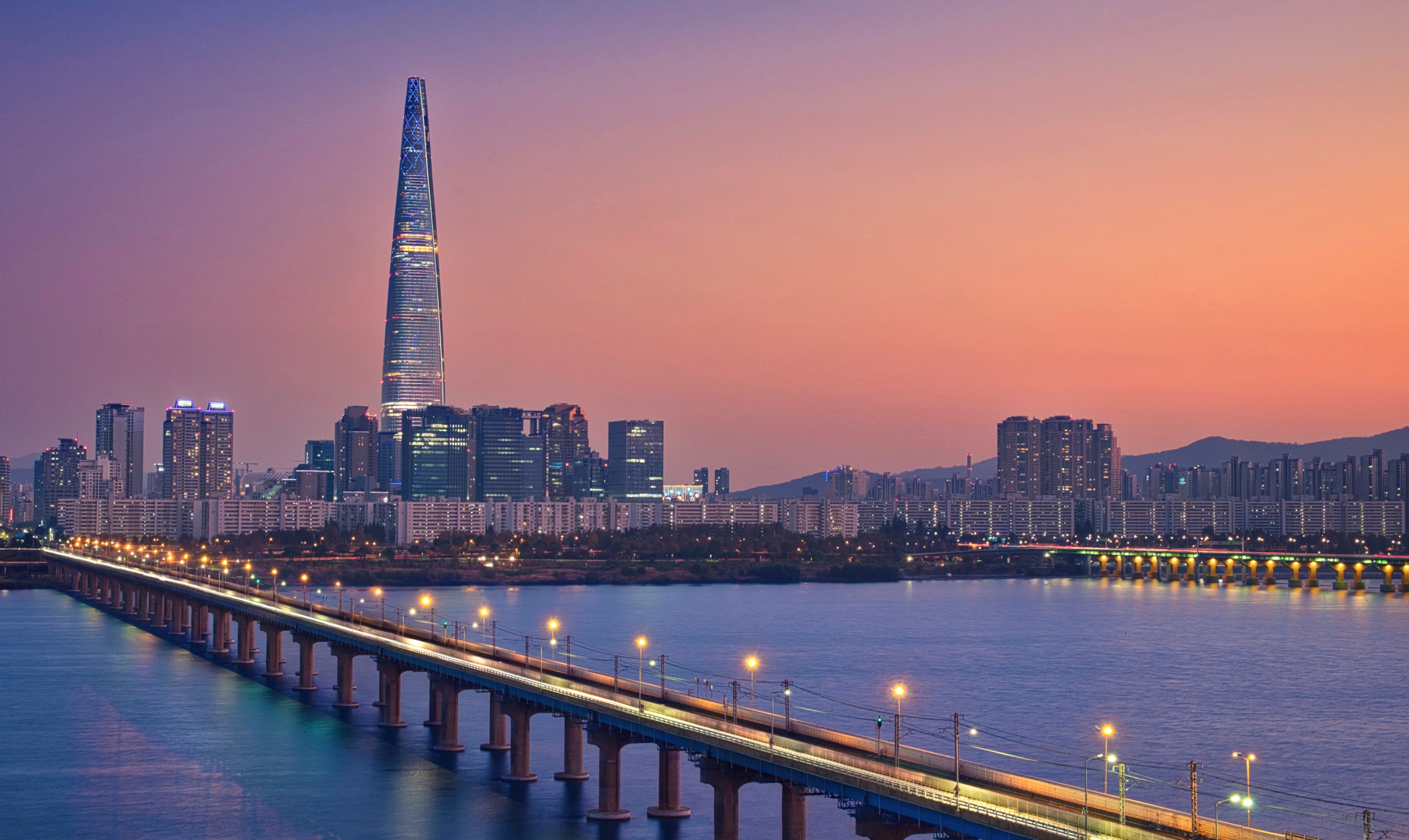 Seoul skyline at sunset, with a bridge and Lotte World Tower.