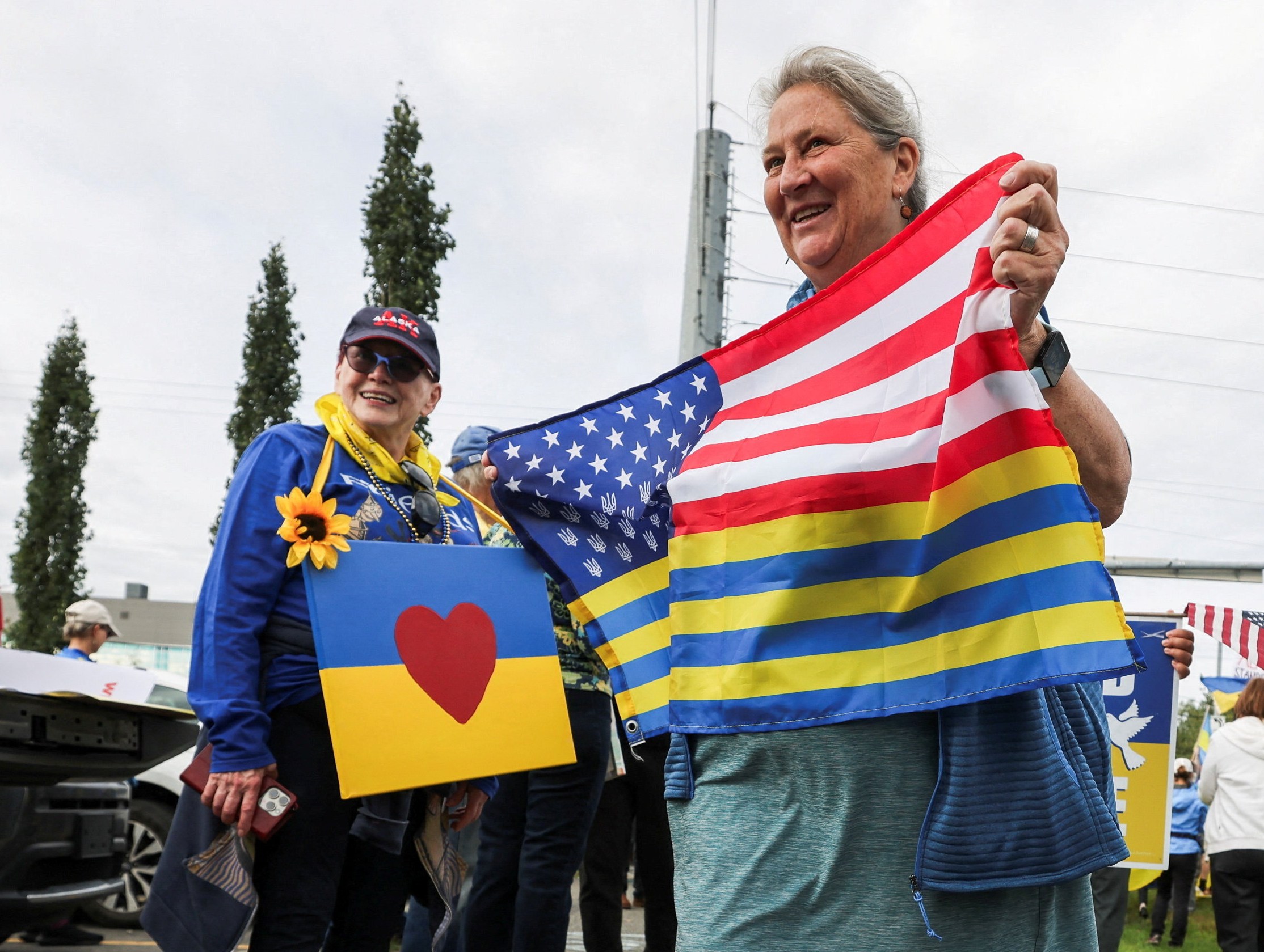 Protestors in Anchorage holding Ukrainian and American flags in solidarity with Ukraine before a Trump-Putin meeting.