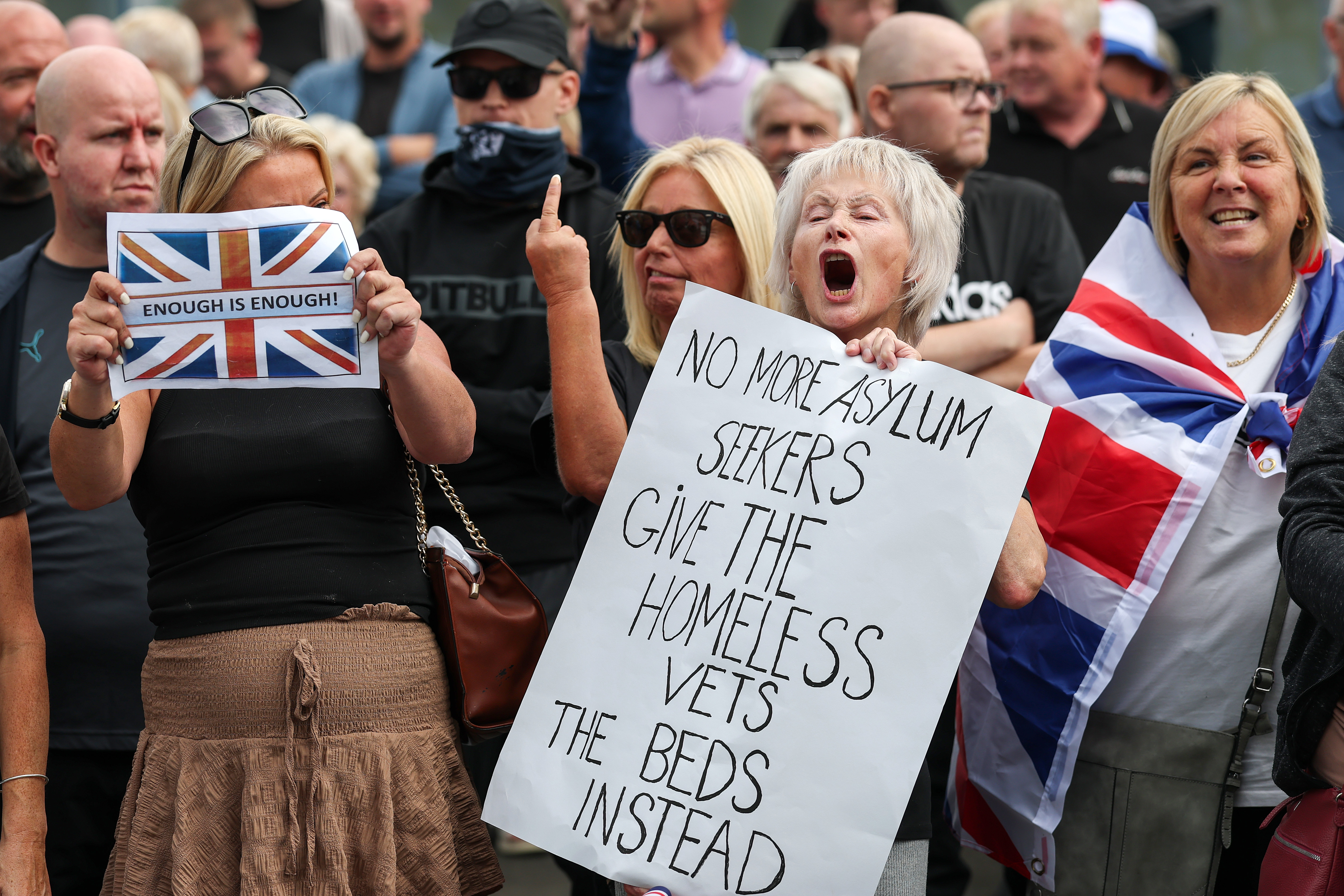 Protestors against asylum seekers hold signs.