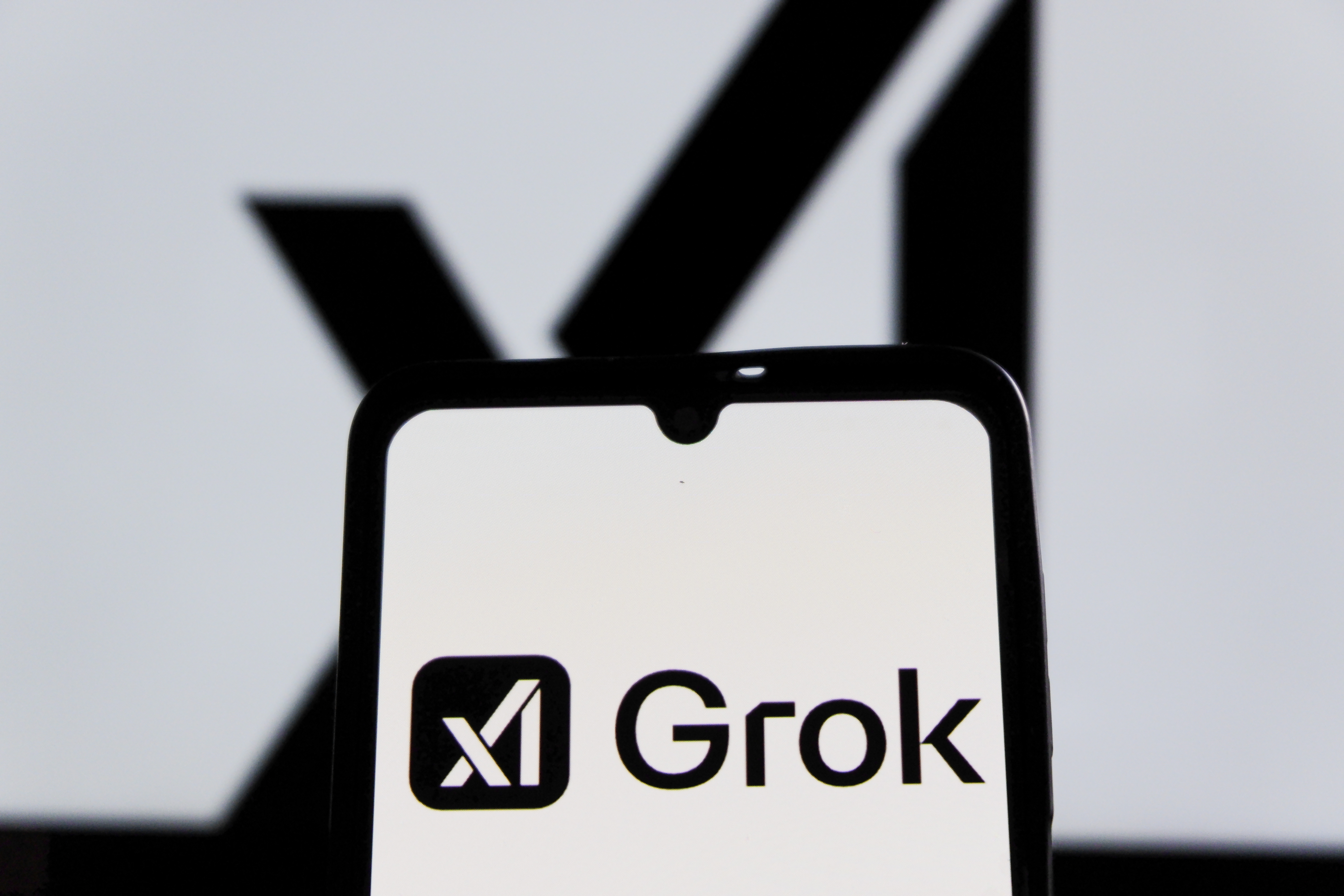 Photo illustration of the xAI Grok logo on a smartphone screen.