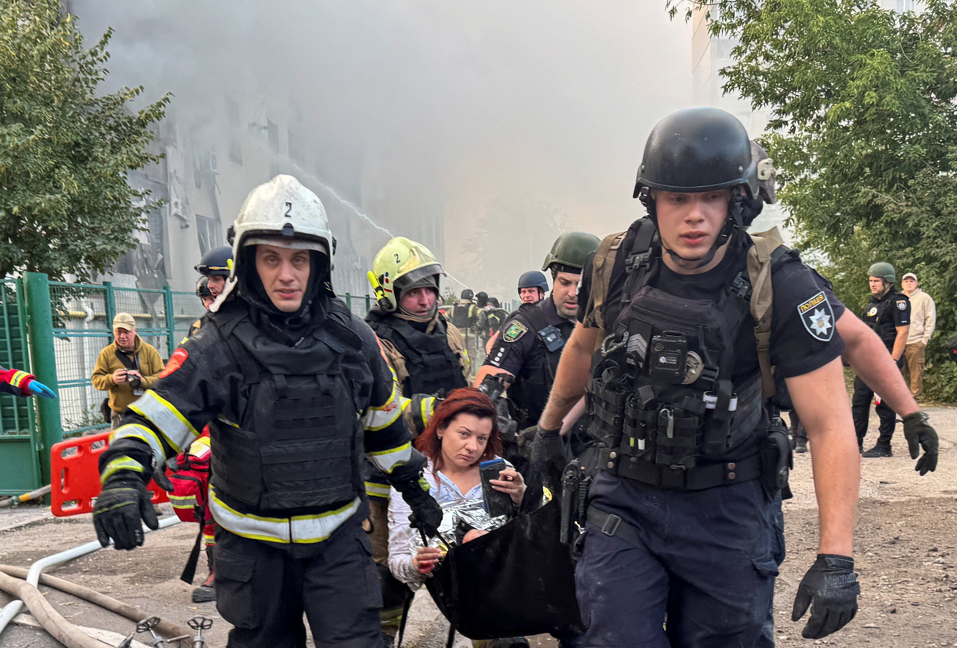 Emergency workers carrying a woman rescued from a damaged apartment building in Kharkiv, Ukraine, following a Russian drone attack.