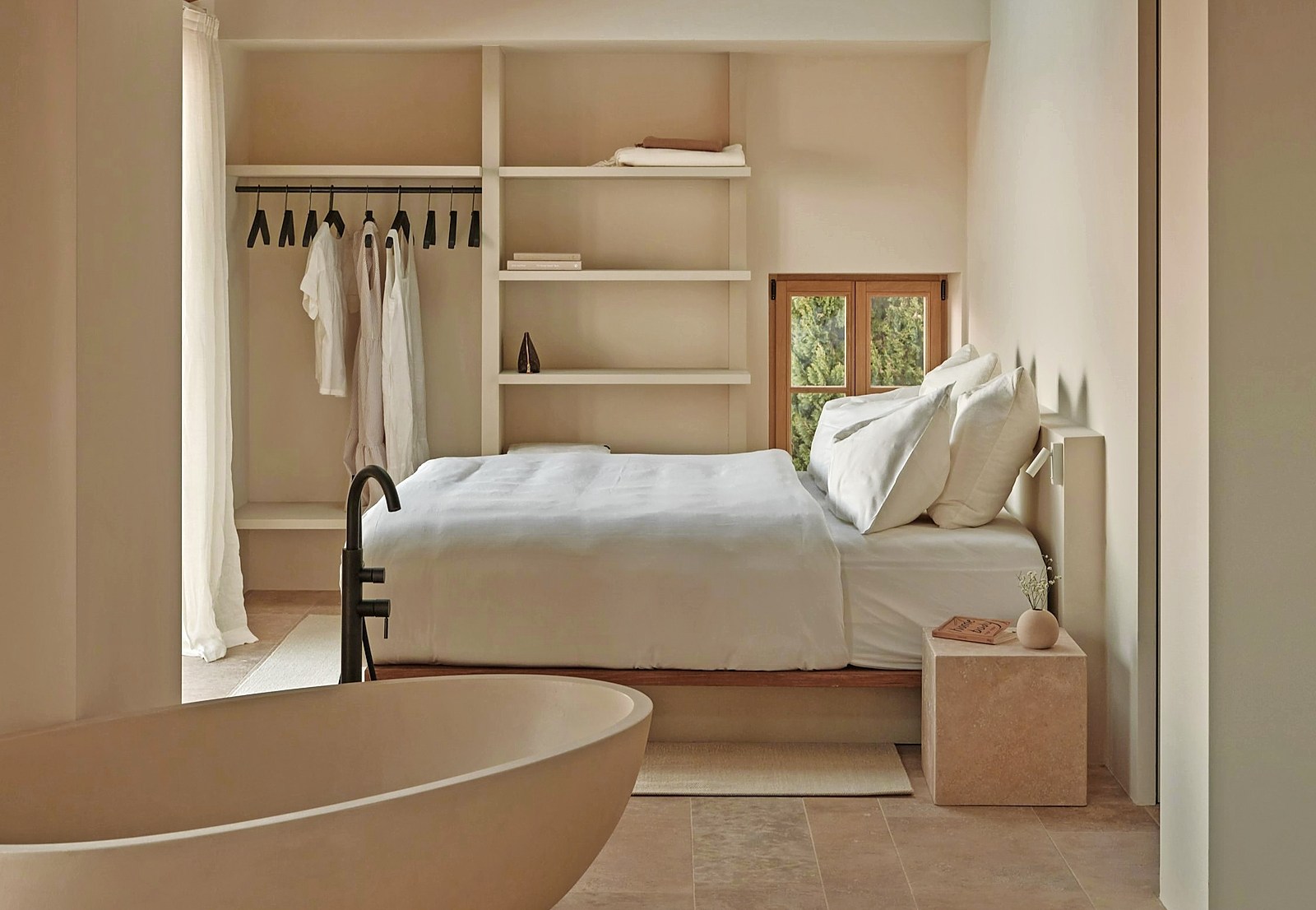 Minimalist bedroom with built-in shelving and freestanding bathtub.