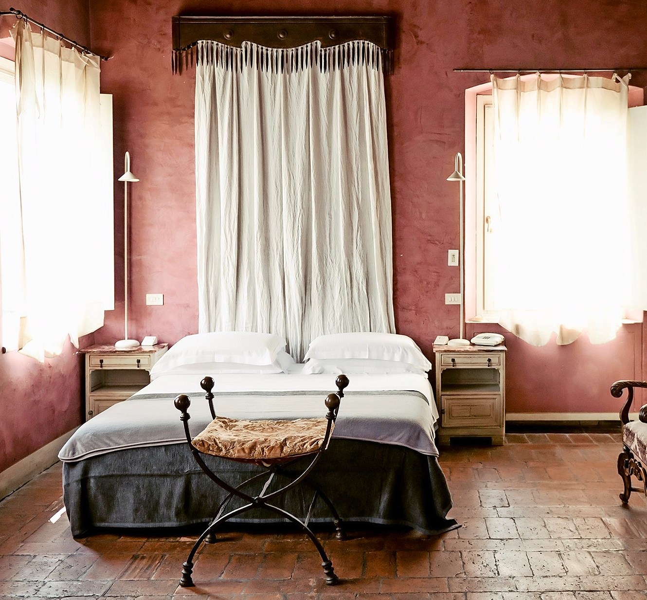 Hotel room with a double bed and terracotta tile floor.