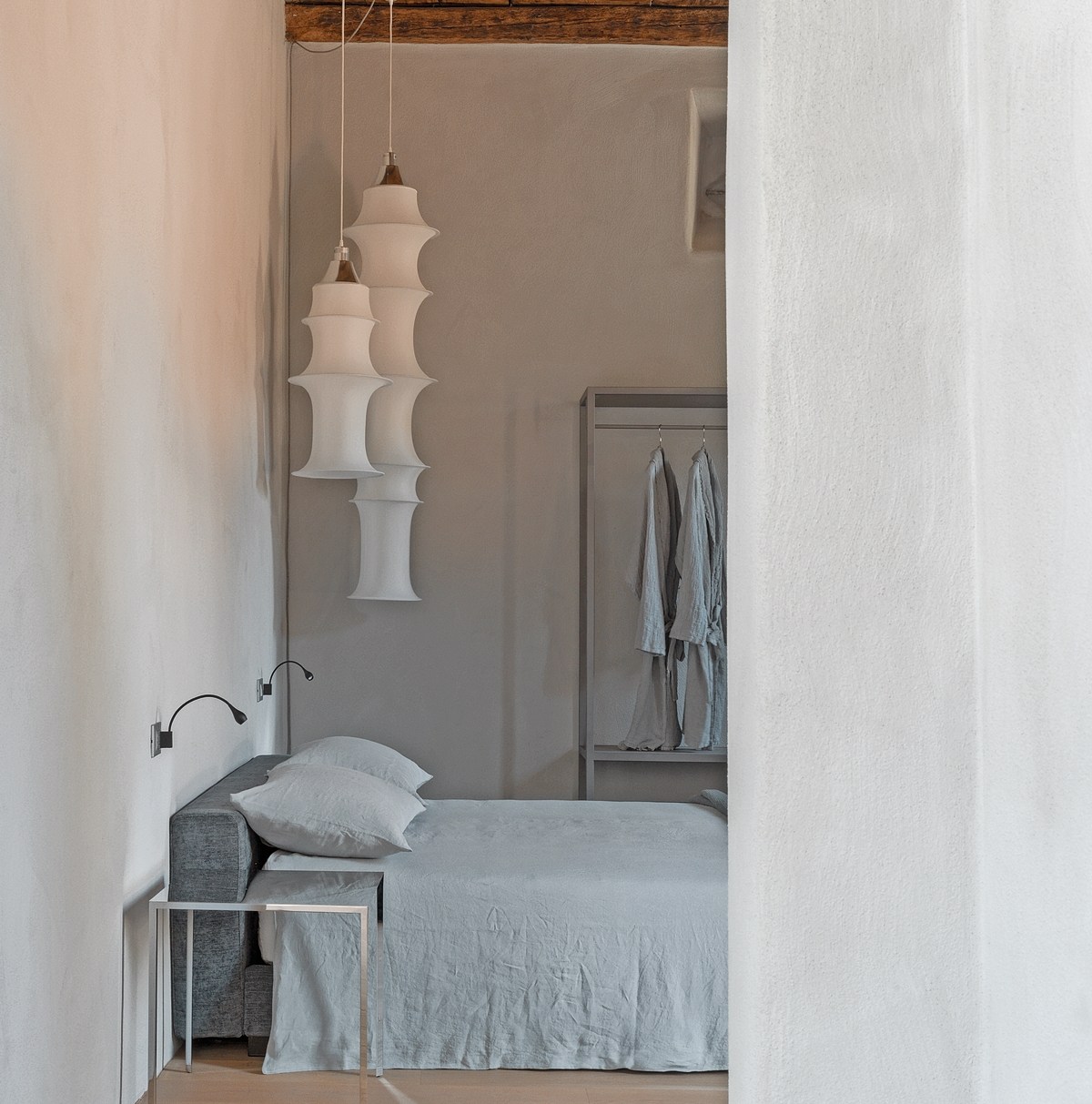 Hotel room with bed and hanging robes.