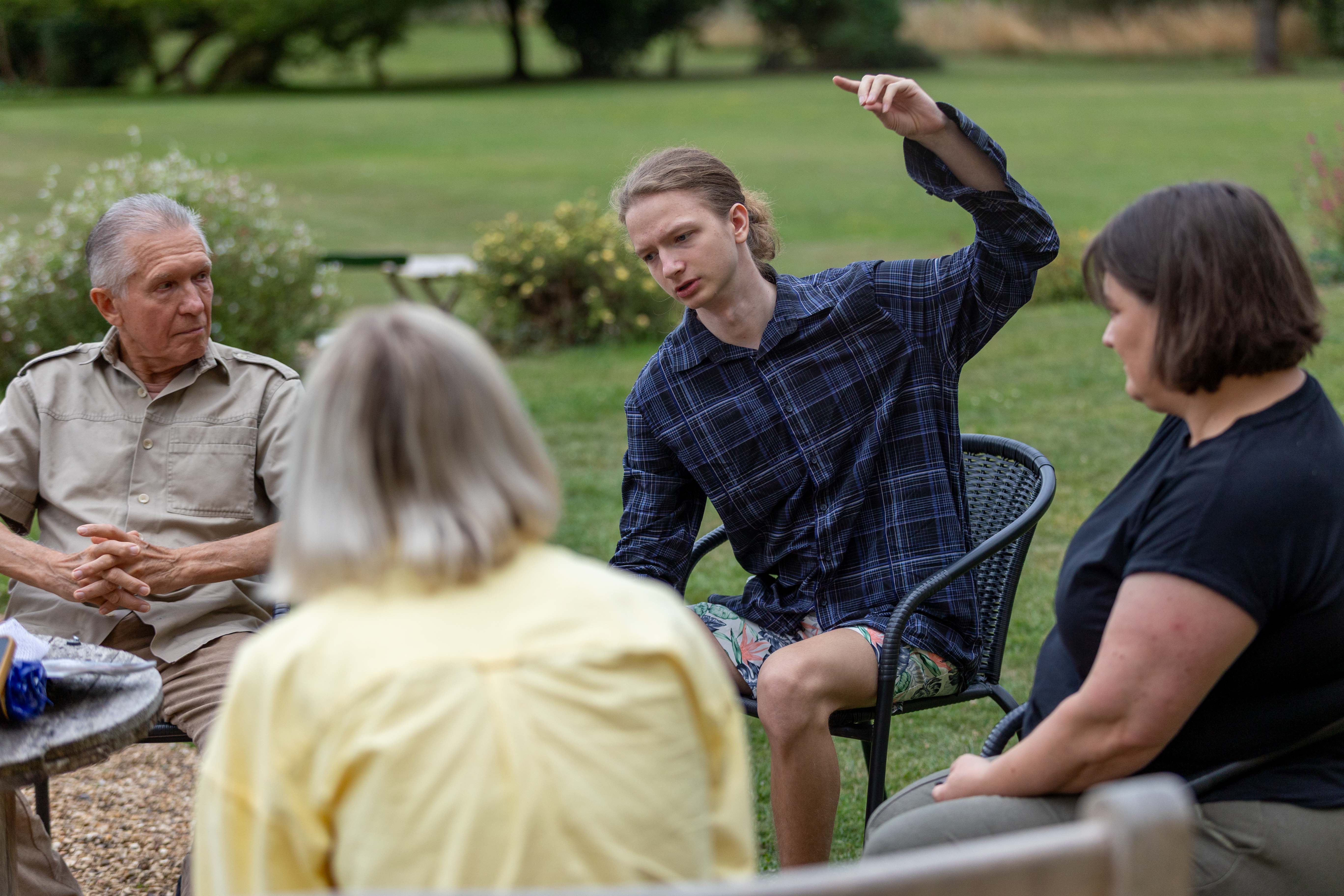 A young Ukrainian man speaks with a group of older adults outdoors.